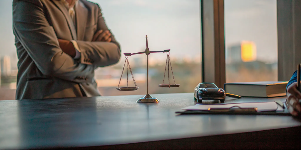 A lawyer's desk with scales of justice, a toy car, and documents for a car accident claim.