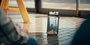 A smartphone on a tiled floor displaying a photograph of a wet floor hazard, showing slip and fall evidence preservation