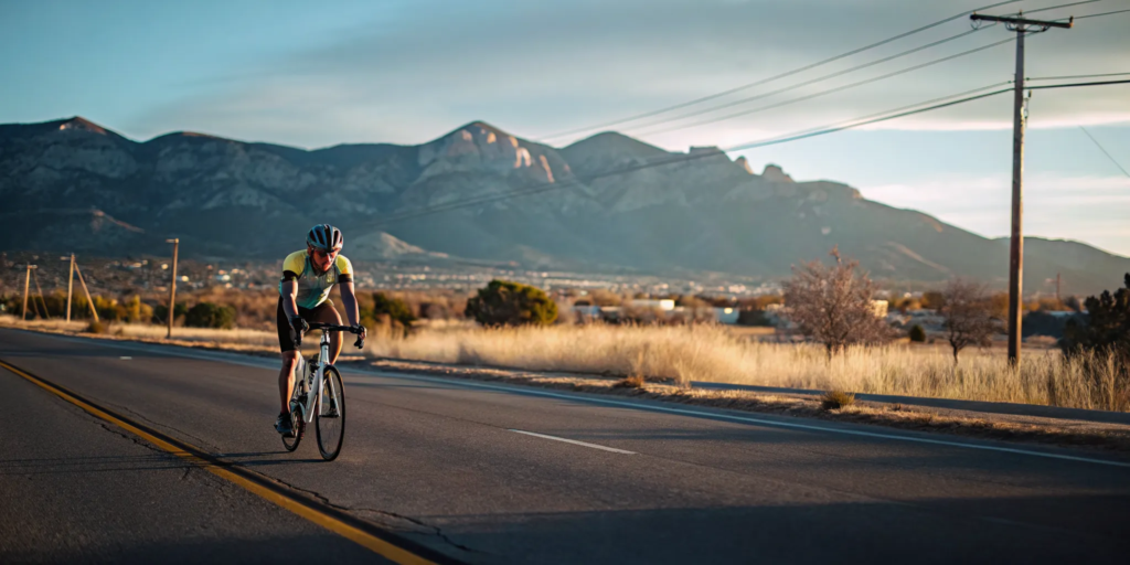 Cyclist riding on a scenic New Mexico road with mountains in the background